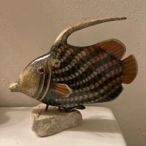 Iridescent ceramic fish sculpture with stone base.